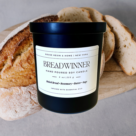A black candle jar in front of a loaf of bread.
