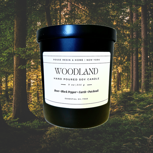 A black candle jar with a forest in the background.